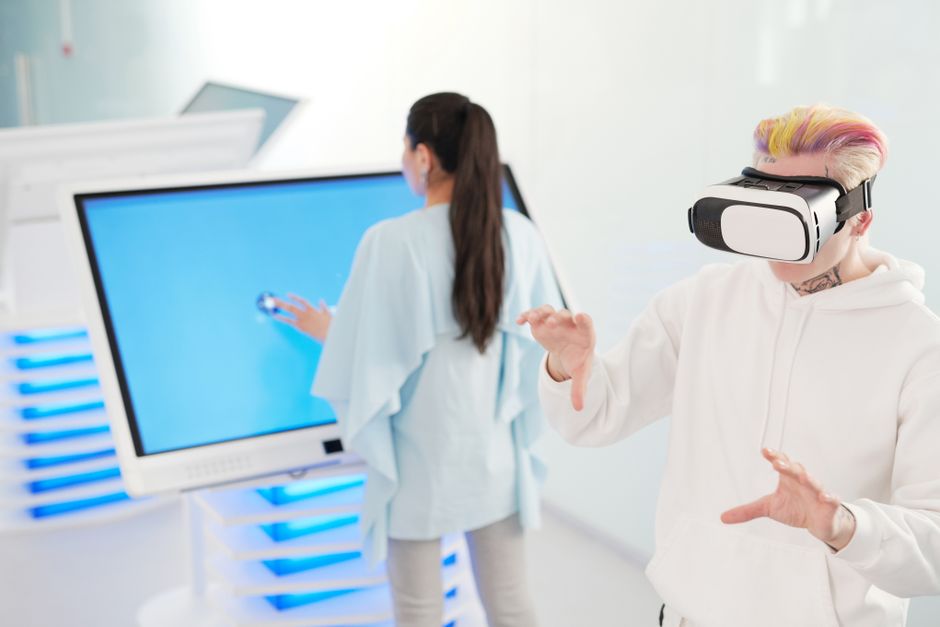 Dos jóvenes interactuando con tecnología VR y pantallas táctiles